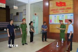 Lực lượng chức năng đọc lệnh khởi tố các đối tượng sản xuất giá đỗ bằng hóa chất độc. (Ảnh TTXVN phát)