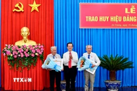 Ông Lê Hồng Quang, Bí thư Tỉnh ủy An Giang trao huy hiệu 65 năm tuổi Đảng cho 2 đảng viên. (Ảnh: Thanh Sang/TTXVN)