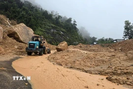 Lực lượng chức năng tỉnh Khánh Hòa huy động thiết bị cơ giới dọn dẹp đất đá bị sạt lở để tiếp cận hiện trường đưa nạn nhân ra ngoài. (Ảnh: Đặng Tuấn/TTXVN)