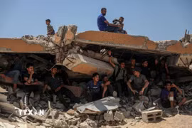 Người dân Palestine ngồi trên đống đổ nát ở khu vực Sudaniya, phía Bắc thành phố Gaza. (Ảnh: THX/TTXVN)