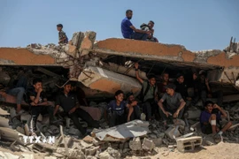 Người dân Palestine ngồi trên đống đổ nát ở khu vực Sudaniya, phía Bắc thành phố Gaza. (Ảnh: THX/TTXVN)