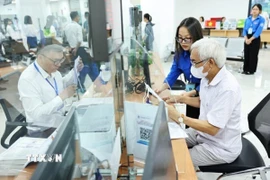 Đội thanh niên tình nguyện hỗ trợ vận hành chính quyền 2 cấp và cung cấp dịch vụ công trực tuyến tại Trung tâm Phục vụ hành chính công phường Cầu Giấy, Hà Nội. (Ảnh: Minh Đức/TTXVN)