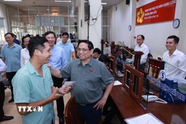 Thủ tướng Phạm Minh Chính thăm hỏi người dân đến làm thủ tục tại Trung tâm Phục vụ hành chính công phường Ninh Kiều. (Ảnh: Dương Giang/TTXVN)