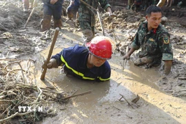 Các chiến sỹ nỗ lực tìm kiếm nạn nhân bị vùi lấp dưới lớp bùn đất. (Ảnh: Xuân Tư/TTXVN)