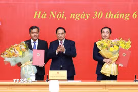 Thủ tướng Phạm Minh Chính trao quyết định và tặng hoa chúc mừng đồng chí Trần Đức Thắng (phải), Phó Tổng Thanh tra Thường trực Thanh tra Chính phủ và đồng chí Hồ Văn Niên, Thứ trưởng Thường trực Bộ Dân tộc và Tôn giáo. (Ảnh: Dương Giang/TTXVN)