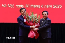Ủy viên Bộ Chính trị, Giám đốc Học viện Chính trị quốc gia Hồ Chí Minh, Chủ tịch Hội đồng Lý luận Trung ương Nguyễn Xuân Thắng trao Quyết định và tặng hoa chúc mừng ông Đoàn Minh Huấn. (Ảnh: Văn Điệp/TTXVN)