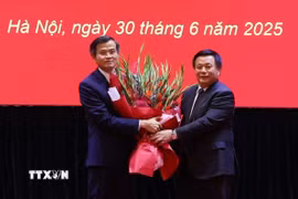 Ủy viên Bộ Chính trị, Giám đốc Học viện Chính trị quốc gia Hồ Chí Minh, Chủ tịch Hội đồng Lý luận Trung ương Nguyễn Xuân Thắng trao Quyết định và tặng hoa chúc mừng ông Đoàn Minh Huấn. (Ảnh: Văn Điệp/TTXVN)