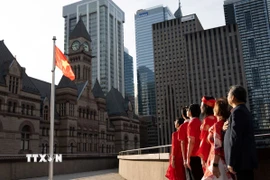 Đại diện cộng đồng người Việt chào cờ tại buổi lễ. (Ảnh: TTXVN phát)