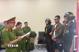 Công an đọc lệnh bắt đối tượng trong đường dây lừa đảo. (Ảnh: TTXVN phát)