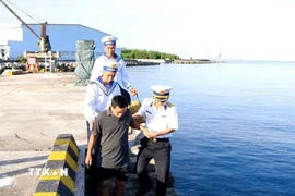 Cán bộ, chiến sỹ thị trấn Trường Sa đưa ông Trần Công Nhanh trở lại tàu để rời đảo. (Ảnh: TTXVN phát)