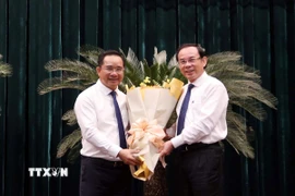 Ông Nguyễn Văn Nên (phải), Ủy viên Bộ Chính trị, Bí thư Thành ủy Thành phố Hồ Chí Minh chúc mừng Chủ tịch Ủy ban Nhân dân Thành phố Hồ Chí Minh Nguyễn Văn Được. (Ảnh: Xuân Khu/TTXVN)
