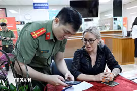 Cán bộ, chiến sỹ Cục quản lý xuất nhập cảnh, Bộ Công an hướng dẫn người nước ngoài làm thủ tục cấp tài khoản định danh điện tử. (Ảnh: Phạm Kiên/TTXVN)