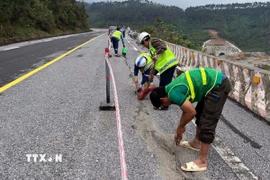 Lực lượng công nhân tiến hành nhồi sợi dây đay vào khe nứt rồi đổ nhựa đường nhằm ngăn nước thấm xuống phía dưới tại sự cố nứt đường trên Quốc lộ 1A, đoạn qua Đèo Ngang. (Ảnh: TTXVN phát)