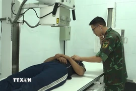 Bác sỹ Bệnh xá Đảo Song Tử Tây đang thăm khám cho bệnh nhân Đặng Ân. (Ảnh: TTXVN phát)