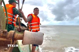 Thuyền viên Võ Văn Hiếu được cán bộ, chiến sỹ Đồn Biên phòng Sông Đốc đưa lên tàu an toàn. (Ảnh: TTXVN phát)