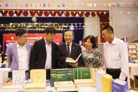 Đại sứ Việt Nam tại Lào Nguyễn Minh Tâm giới thiệu sách tại gian trưng bày của Việt Nam. (Ảnh: Xuân Tú/TTXVN)
