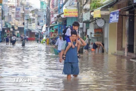 Một học sinh được người thân cõng đến trường do đường Bùi Hữu Nghĩa (phường Bình Thủy) bị ngập ngày 8/10. (Ảnh: Thanh Liêm/TTXVN)
