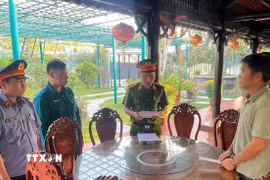 Cơ quan Cảnh sát điều tra Công an tỉnh Quảng Nam đọc quyết định khởi tố đối tượng Bùi Ngọc Dũng (phải). (Ảnh: Trần Tĩnh/TTXVN)
