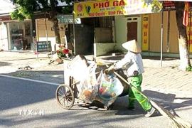 Người lao công quét đường từ sớm nhưng vẫn không tránh được ánh mặt trời gay gắt ngày hè nắng gắt. Ảnh chụp tại đường Chùa Hà phường Vĩnh Phúc, tỉnh Phú Thọ. (Ảnh: Hoàng Hùng/TTXVN)