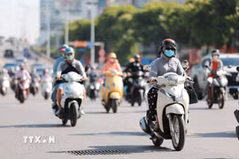 Người dân sử dụng khẩu trang, áo chống nắng giúp tránh nóng bức khi tham gia giao thông. (Ảnh: Lê Đông/TTXVN)