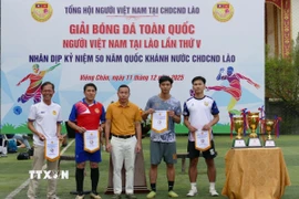Đại diện Tổng hội người Việt Nam tại Lào trao cờ lưu niệm cho các đội tham dự giải đấu. (Ảnh: Xuân Tú/TTXVN)