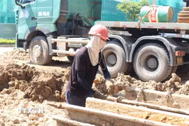 Công nhân căng mình làm việc trong điều kiện thời tiết nắng nóng gay gắt để đảm bảo tiến độ dự án. (Ảnh: Nguyễn Thắng/TTXVN)