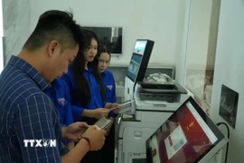 Hỗ trợ người dân khi làm thủ tục trực tuyến. (Ảnh: Hữu Duyên/TTXVN)