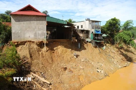 Sau khi lữ dữ càn quét qua, nhiều ngôi nhà của người dân trên địa xã Mường Xén (tỉnh Nghệ An) nằm chênh vênh bên bờ vực sông Nậm Mộ, nguy cơ sạt lở rất cao. (Ảnh: Xuân Tiến/TTXVN)