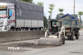 Thu gom lớp áo đường bị hư hỏng. (Ảnh: Mai Trang/TTXVN)