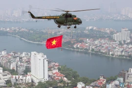 Biên đội máy bay trực thăng của Quân chủng Phòng không-Không quân treo cờ Đảng và cờ Tổ quốc bay vào khu vực trung tâm Thủ đô Hà Nội. (Ảnh: Trọng Đức/TTXVN)