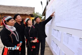 Cử tri xem danh sách đại biểu ứng cử được niêm yết công khai tại nhà văn hóa thôn Nặm Đăm, xã Quản Bạ. (Ảnh: Minh Đức/TTXVN)