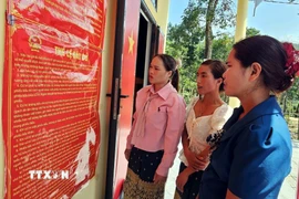 Đồng bào Bru - Vân Kiều (xã Trường Sơn, Quảng Trị) đọc các quy định về công tác bầu cử. (Ảnh: TTXVN phát)