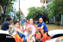 Người dân được lực lượng chức năng tỉnh Lào Cai hỗ trợ di chuyển đến nơi an toàn. (Ảnh: Tuấn Anh/TTXVN)