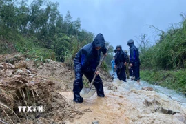 Các lực lượng đào, vét đất đá, mở rãnh thoát nước và thu dọn bùn đất tràn xuống mặt đường, tạo lối đi tạm để phương tiện qua lại. (Ảnh: TTXVN phát)