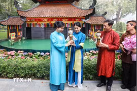 Bà Ngô Phương Ly, Phu nhân Tổng Bí thư Tô Lâm tặng con rối nước cho bà Loo Tze Lui, Phu nhân Thủ tướng Singapore Lawrence Wong. (Ảnh: Phạm Kiên/TTXVN)