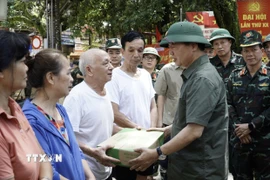 Phó Thủ tướng Trần Hồng Hà tặng quà các hộ bị ngập hoàn toàn. (Ảnh: Chu Hiệu/TTXVN)