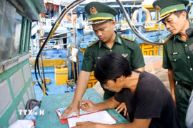 Cán bộ Đồn Biên phòng hướng dẫn ngư dân ký cam kết không vi phạm IUU. (Ảnh: Hồng Hiếu/TTXVN)
