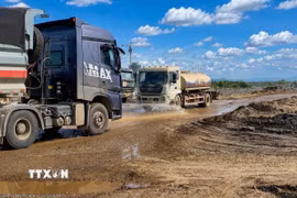 Đơn vị thi công tăng cường bố trí liên tục các xe chuyên dụng thay nhau tưới nước dọc các tuyến đường công vụ nhằm hạn chế tối đa tình trạng bụi bay vào khu dân cư. (Ảnh: TTXVN phát)
