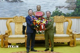 Đại sứ Việt Nam tại Lào Nguyễn Minh Tâm tặng hoa chúc mừng Bộ Công an Lào nhân dịp Kỷ niệm 50 năm Quốc khánh Lào và 105 Ngày sinh Chủ tịch Kaysone Phonvihane. (Ảnh: Xuân Tú/TTXVN)