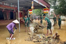 Cán bộ chiến sĩ Trung đoàn 95 giúp người dân dọn dẹp khắc phục hậu quả lũ lụt tại xã Tam Giang. (Ảnh: Danh Lam/TTXVN)