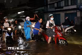 Sinh viên hỗ trợ người dân đẩy xe lên các điểm cao chờ nước rút. (Ảnh: Thanh Liêm/TTXVN)
