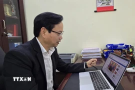 Tiến sỹ Nguyễn Đình Hoàng nghiên cứu thông tin về Đại hội Đại biểu toàn quốc lần thứ XIV của đảng trên website của Thông tấn xã Việt Nam. (Ảnh: Minh Thu/TTXVN)