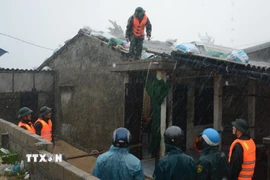 Các cán bộ chiến sỹ Bộ đội Biên phòng bất chất mưa gió, nguy hiểm tích cực hỗ trợ người dân sống ven biển chằng chống nhà cửa. (Ảnh: Văn Dũng/TTXVN)