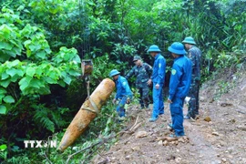 Lực lượng chức năng di dời quả bom đến nơi hủy nổ. (Ảnh: TTXVN phát)