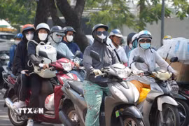 Người dân thành phố Huế mặc đồ bảo hộ chống nắng, khi di chuyển trên đường Trần Hưng Đạo, phường Phú Xuân. (Ảnh: Nguyên Lý/TTXVN)