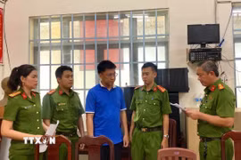 Cơ quan chức năng tống đạt quyết định khởi tố, bắt tạm giam đối với Nguyễn Anh Tiến. (Ảnh: TTXVN phát)