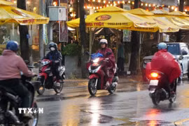 Người dân phường Mỹ Tho tham gia giao thông dưới cơn mưa chiều 15/5. (Ảnh: Hồng Thái/TTXVN)