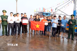 Phó Chủ tịch UBND tỉnh Quảng Trị Lê Văn Bảo (hàng trên, thứ 4 từ phải sang) tặng quà và nhắc nhở ngư dân thực hiện nghiêm các quy định chống khai thác IUU. (Ảnh: Tá Chuyên/TTXVN)
