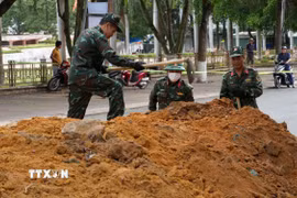 Lực lượng chức năng tiến hành đào rãnh thăm dò dọc đường Trường Chinh (Quảng Ngãi). (Ảnh: Dư Toán/TTXVN)