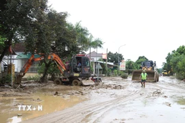 Máy cẩu, máy xúc được huy động tham gia vào việc san ủi bùn đất, sinh lầy tại một điểm ngập trên tuyến quốc lộ 7 qua địa bàn xã Con Cuông, tỉnh Nghệ An. (Ảnh: Xuân Tiến/TTXVN)